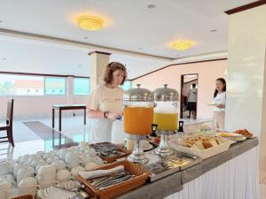 a woman standing behind a counter with a buffet of food at Vangvieng Sisavang Mountain View Hotel in Vang Vieng