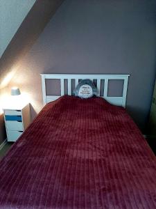 a bed with a red bedspread and a clock on it at Heide Nest Soltau in Soltau