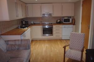 a kitchen with white cabinets and a couch in it at Drummond Apartment in Edinburgh