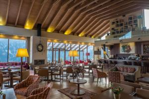 restauracja ze stołami, krzesłami i oknami w obiekcie Orizontes Tzoumerkon Hotel Resort w mieście Pramanta