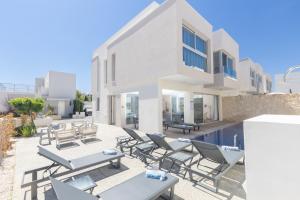 a villa with a swimming pool and patio furniture at Mythical Blue Villas in Protaras