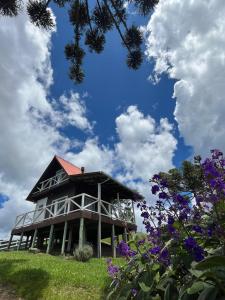 a house on top of a hill with purple flowers at Cabana Sítio Costãozinho in Bom Retiro