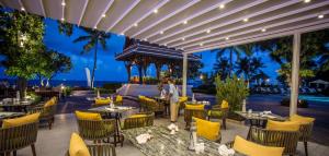 a restaurant with yellow chairs and tables with the ocean in the background at Centara Grand Beach Resort Hua Hin in Hua Hin