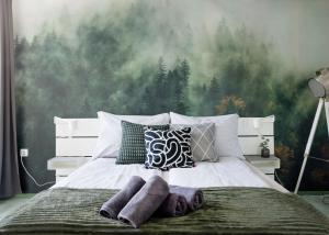 a bedroom with a bed with a forest wallpaper at Riverside Apartman**** Miskolc in Miskolc