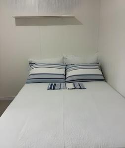 a white bed with two pillows on top of it at Cantinho Charmoso Pertinho do Mar in Navegantes