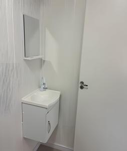 a white bathroom with a sink and a mirror at Cantinho Charmoso Pertinho do Mar in Navegantes
