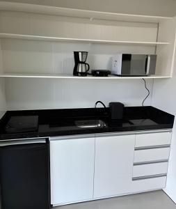 a kitchen with a stove and a microwave at Cantinho Charmoso Pertinho do Mar in Navegantes +7 photos