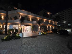 a large white building with palm trees and lights at Hotel Miami Beach in Golem