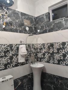 a bathroom with black and white tiles and a sink at Hotel Aqua Waterfall in Dharamshala +35 photos