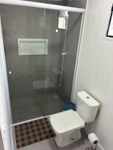 a bathroom with a toilet and a glass shower at Refúgio ensolarado a poucos passos do mar in Navegantes +8 photos