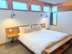 a bedroom with a bed with a wooden frame and windows at Cedar Peak - Design-Forward Barrier-Free Chalet in Grand-Etang