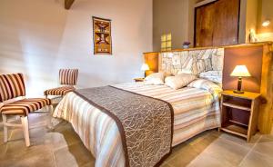 a bedroom with a large bed and two chairs at Blumenau Apart Hotel in Villa General Belgrano