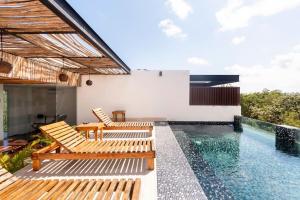 a house with a swimming pool and two wooden chairs at Swim up pool Beachclub rooftop in Tulum