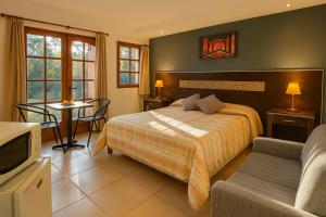 a bedroom with a bed and a couch and a tv at Blumenau Apart Hotel in Villa General Belgrano