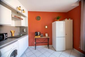 a kitchen with an orange wall and a white refrigerator at Studio Equerre in Toulon +3 photos