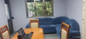 a living room with a blue couch and a table with a laptop at Enjoy Hostel in Tirana