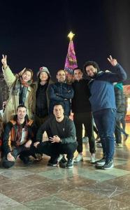 a group of people standing in front of a christmas tree at Enjoy Hostel in Tirana