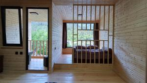 a bedroom with a bed in a room with windows at Eco Cottage Rose in Borjomi
