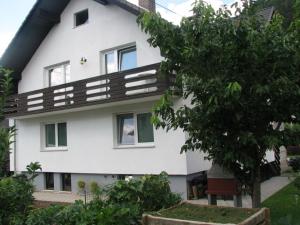 Una casa blanca con un árbol delante. en Apartment Marinka, en Bled