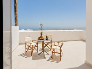 a table and chairs on a balcony with a view of the ocean at Aurora Sky & Sea in Fira