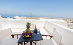 a table with a bowl of fruit and a bottle of wine at Aurora Sky & Sea in Fira