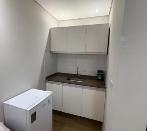 a small kitchen with white cabinets and a sink at Joseph Prime Studio Hotel Extrema MG in Extrema +32 photos