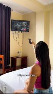 a woman sitting on a bed playing a video game at Hostal La Gata in Tingo María