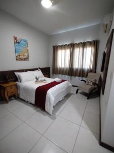 a bedroom with a bed and a chair in it at Miotto Executive Hotel in Navegantes