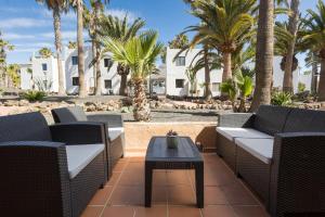 a patio with chairs and a table and palm trees at Casa Nube in Corralejo