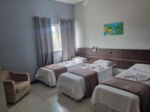 a hotel room with three beds and a chair at Miotto Executive Hotel in Navegantes