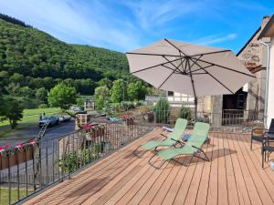 a patio with two chairs and an umbrella on a deck at B&B Haus Valmosa in Valwig