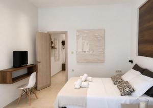 a white bedroom with a bed and a tv at Aelia Living in Stavros