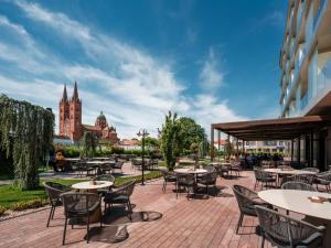 a patio with tables and chairs in front of a building at Diaco Boutique Hotel in Đakovo