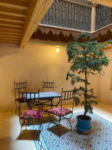 a table and two chairs and a tree in a room at Riad Nassar in Chefchaouen