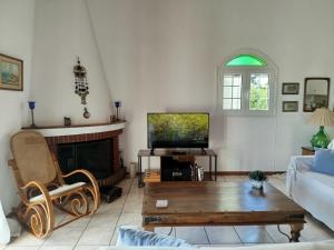 a living room with a couch and a tv at Votsalo Summer House by the Beach in Porto Heli