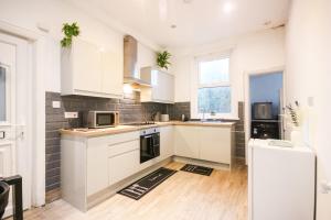a kitchen with white cabinets and a refrigerator at Charming - 8ight Havens in Folkestone