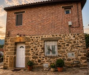 a brick building with a white door and a window at El Nidito del valle del Tietar in La Iglesuela