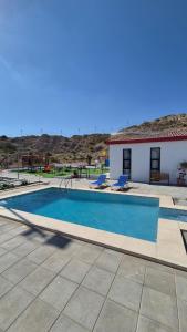 a swimming pool with two chairs and a house at Jory Hatta Resort - منتجع جوري حتا in Hatta