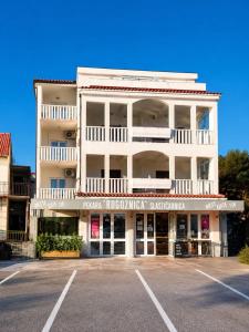 a large white building with a parking lot at Ap AS in Rogoznica +2 photos