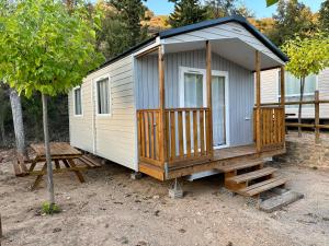 a tiny house with a porch and a deck at Camping Rio Vero de Alquézar in Alquézar