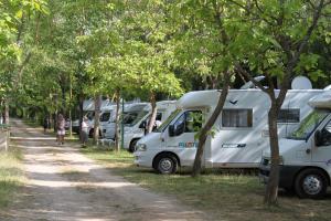 a row of white rvs parked in trees at Camping Rio Vero de Alquézar in Alquézar