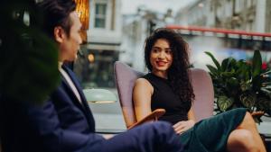 a woman sitting in a chair talking to a man at Ruby Frida Hotel Stockholm by IHG in Stockholm +83 photos