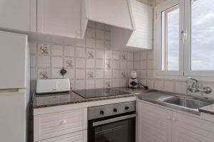 a white kitchen with a sink and a microwave at Villas 84 Est & Oest, Son Bou By MENORCARENTALS in Son Bou