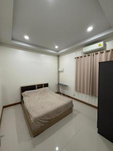 a bedroom with a bed in a room with a window at Happy day in Nong Prue