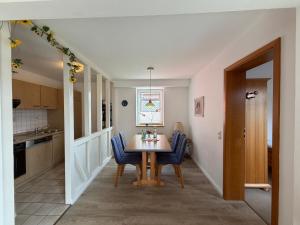 a kitchen with a dining room table and blue chairs at Zum Fahrensmann in Norddorf