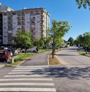 an empty street with a tree and a building at Opal Skay Apartment in Doboj