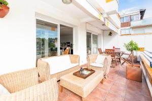 a patio with wicker chairs and a table on a balcony at Marvista - Bright Apt w Seaview, Pool in Sant Pere de Ribes