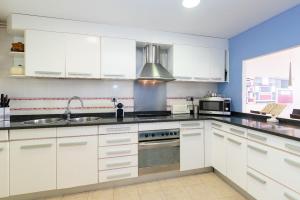 a kitchen with white cabinets and a sink at Marvista - Bright Apt w Seaview, Pool in Sant Pere de Ribes
