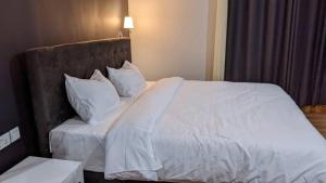 a bed with white sheets and pillows in a room at Mansarda Park View Hotel in Nyagatare +19 photos