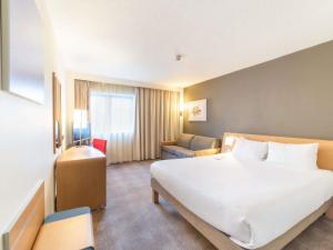a hotel room with a large white bed and a chair at Novotel Southampton in Southampton